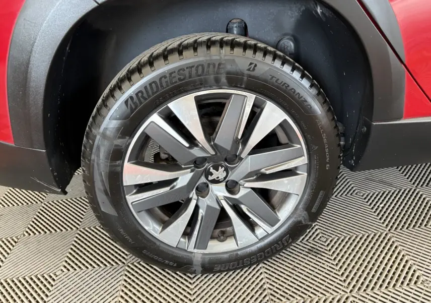 Gros plan sur la roue avant droite avec jante alliage et carrosserie rouge du Peugeot 2008 Puretech 110 Allure 2019.