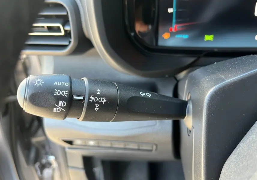 Gros plan sur la commande des feux et clignotants du Citroën Berlingo gris Artense, côté gauche du volant.