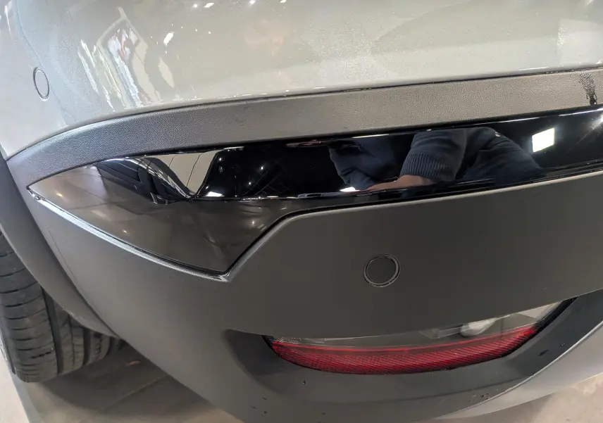 Gros plan sur le pare-chocs arrière gris Rafale de la Renault Symbioz avec un insert noir brillant et un feu rouge inférieur.