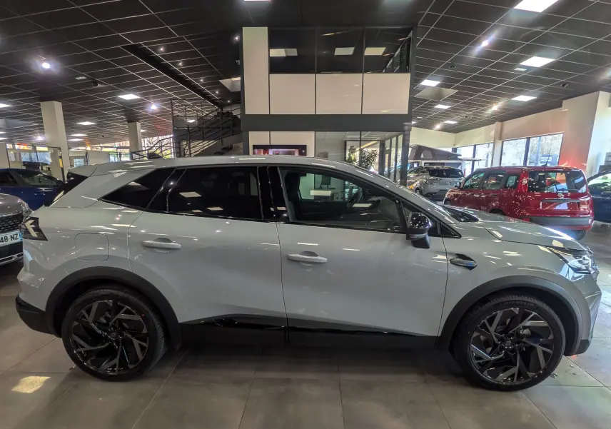 Vue de profil côté gauche du Renault SYMBIOZ gris Rafale 2026 avec jantes noires et toit contrasté en showroom.
