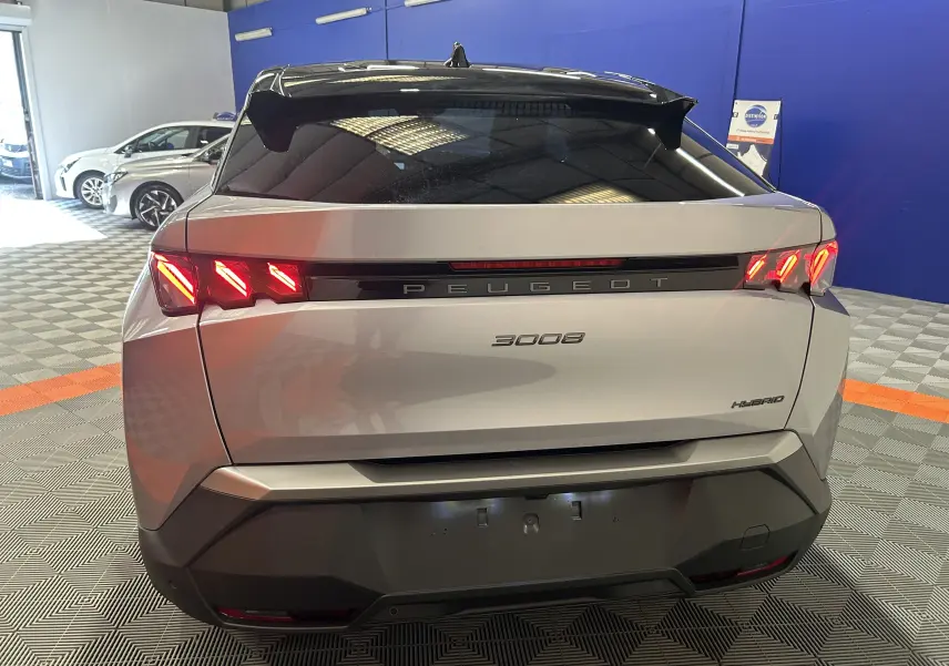 Vue arrière d’un Peugeot 3008 gris Artense avec feux LED allumés et hayon électrique en intérieur showroom.