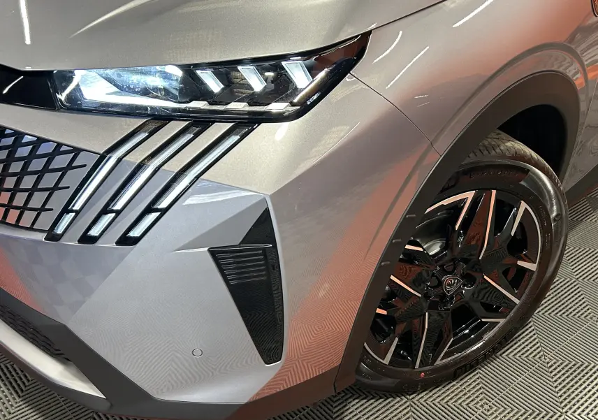 Gros plan sur l’avant droit gris Artense du Peugeot 3008 Hybrid avec phares LED et jante alliage noire brillante.