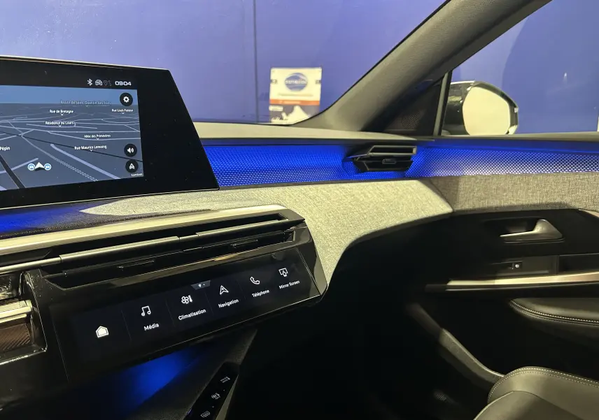 Vue intérieure côté passager du Peugeot 3008 Hybrid 2026, avec éclairage d’ambiance bleu et écran tactile de navigation.