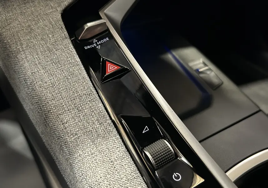 Gros plan sur la console centrale noire et grise du Peugeot 3008 Hybrid avec bouton triangle rouge d’alerte et molette Drive Mode.