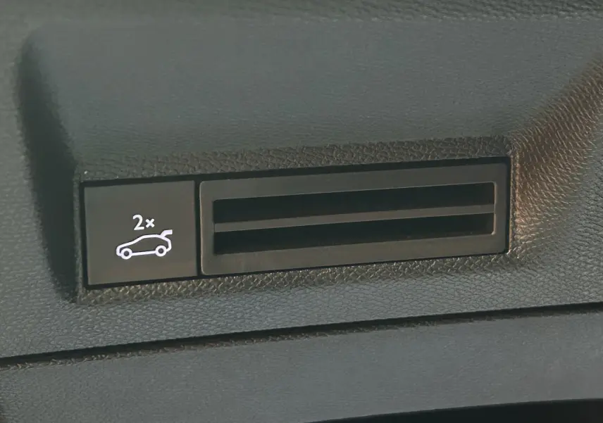 Gros plan sur le bouton d'ouverture électrique du hayon dans l'habitacle du Peugeot 3008 gris Artense.