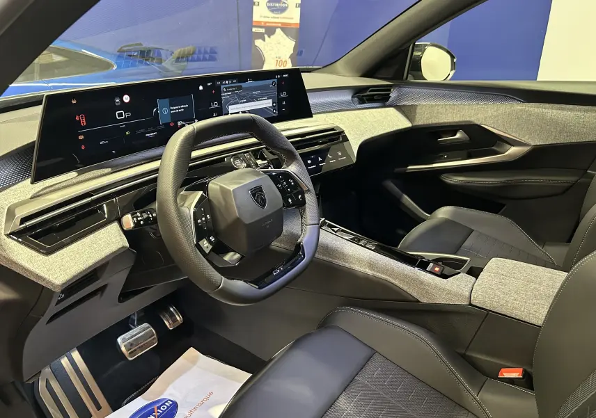 Vue intérieure côté conducteur du Peugeot 3008 III Hybrid avec tableau de bord numérique et finitions tissu gris et cuir noir.
