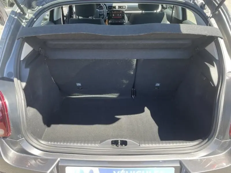 Coffre ouvert vu de l'arrière d'une Citroën C3 82 CV Feel gris foncé métal, intérieur spacieux et banquette arrière visible.