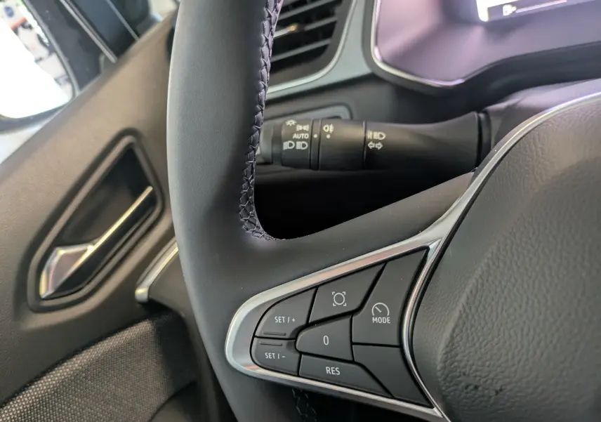 Gros plan sur le volant et les commandes de régulateur de vitesse du Renault Captur 2025, intérieur tissu gris.