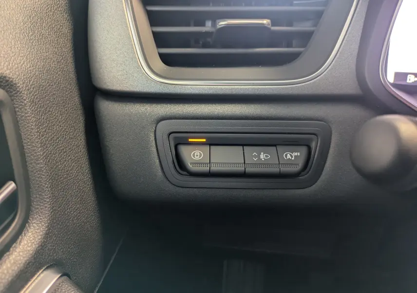 Gros plan sur les commandes de verrouillage centralisé et réglage des phares dans l'habitacle du Renault Captur 2025.