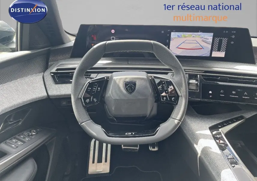Vue frontale du poste de conduite du Peugeot 5008 Hybrid GT 2025, volant compact et écran numérique avec caméra de recul.