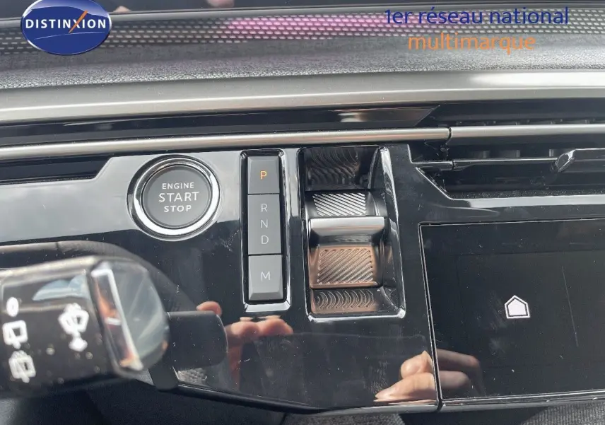 Gros plan sur la console centrale noire perle métal du Peugeot 5008 Hybrid 2025 avec bouton start et commandes de boîte auto.