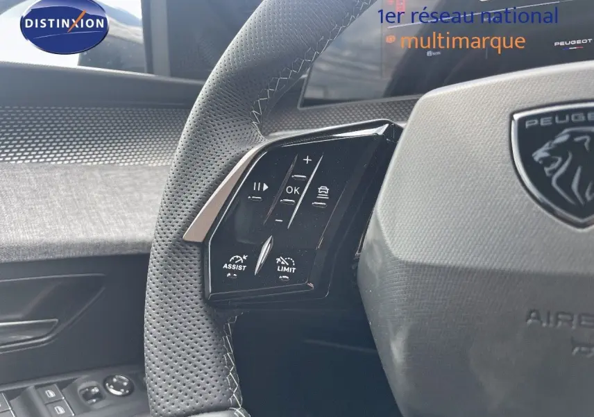 Gros plan sur le volant perforé et les commandes multifonctions du Peugeot 5008 Hybrid noir perle métal.