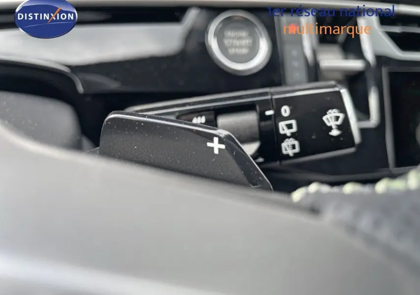 Gros plan sur la palette de changement de vitesse + au volant d’un Peugeot 5008 noir perle hybride 2025.
