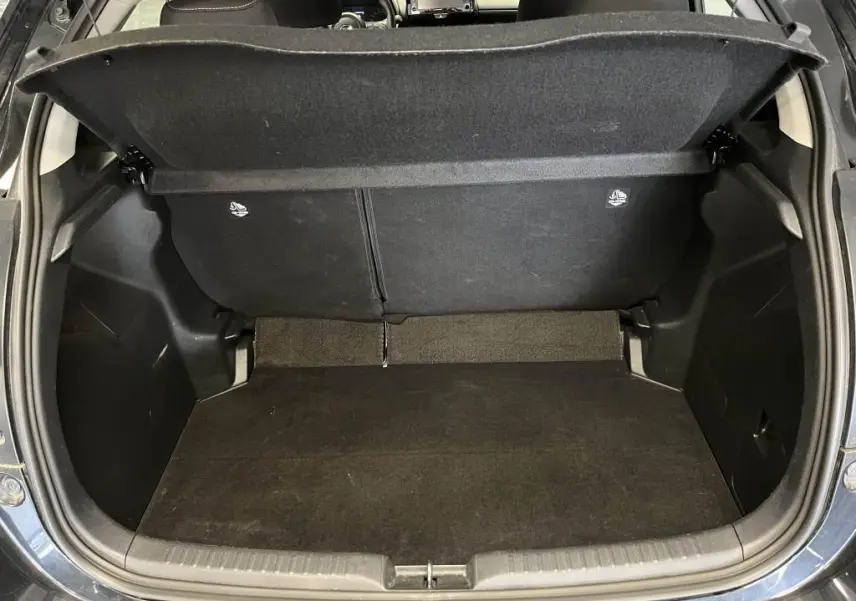 Coffre ouvert vu de l'arrière d'une Mazda2 noire 2023, montrant l'espace de chargement et la tablette cache-bagages.