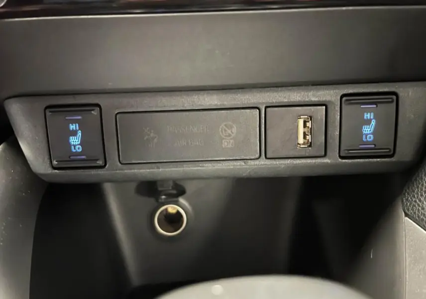 Panneau de commandes intérieur noir de la Mazda2 2023 avec boutons chauffants sièges avant et prise USB visible.