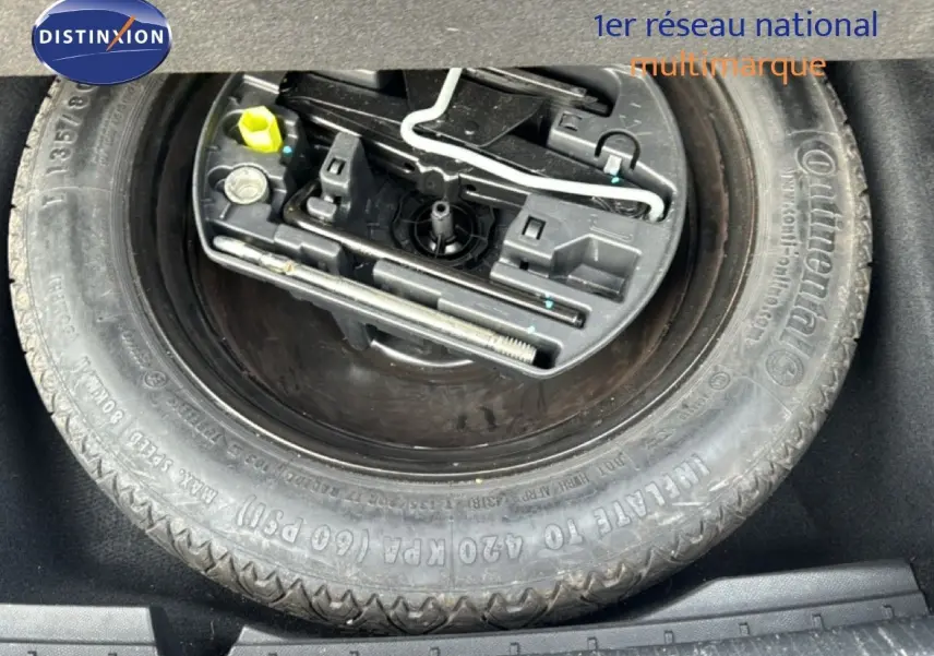 Gros plan sur la roue de secours avec outils intégrés dans le coffre d'une Peugeot 508 gris platinium.