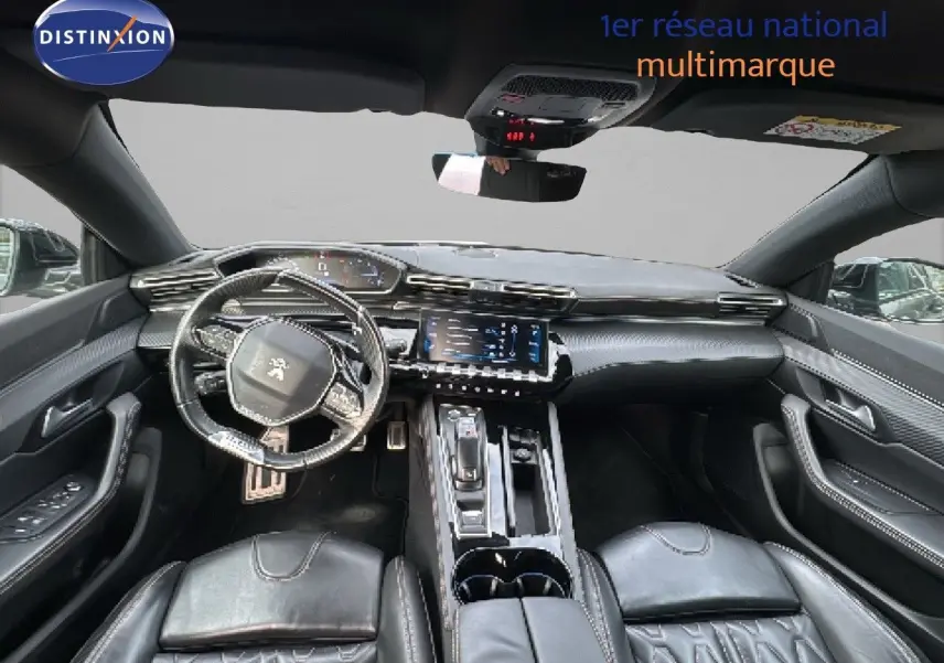 Vue intérieure avant du Peugeot 508 gris platinum 2020, mettant en valeur le tableau de bord et les sièges en cuir noir.