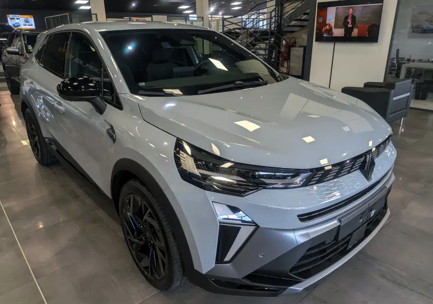 Vue 3/4 avant droite d'une Renault SYMBIOZ E-TECH Full Hybrid gris Rafale avec jantes noires en showroom.