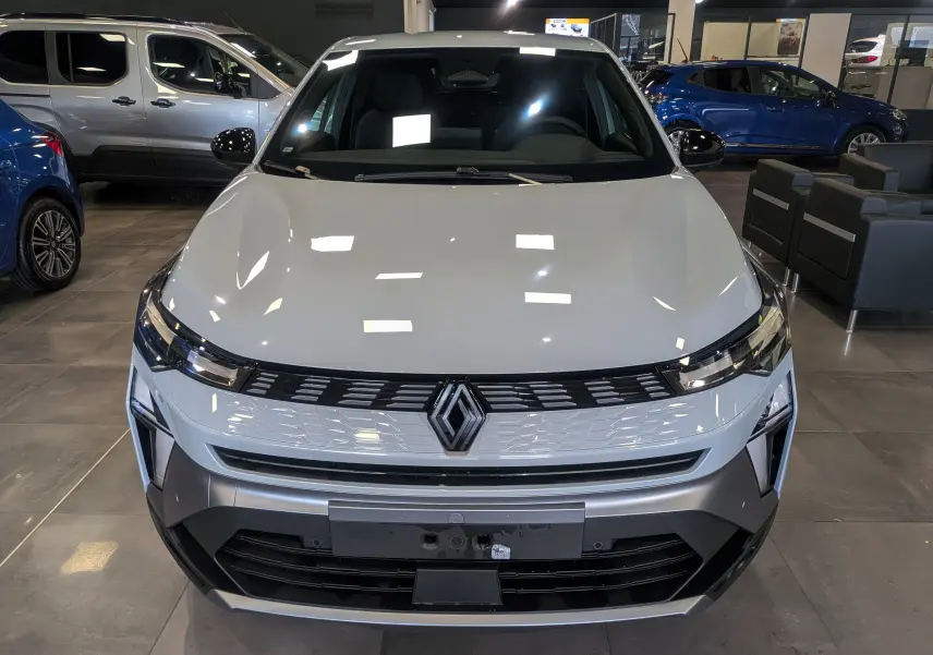 Vue avant d'une Renault SYMBIOZ gris rafale en showroom, avec calandre moderne et logo central distinctif.