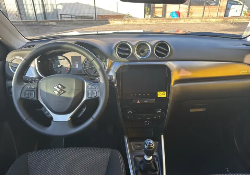 Vue intérieure frontale du tableau de bord et volant cuir multifonctions du Suzuki Vitara Hybrid 2025 avec écran tactile 9 pouces.