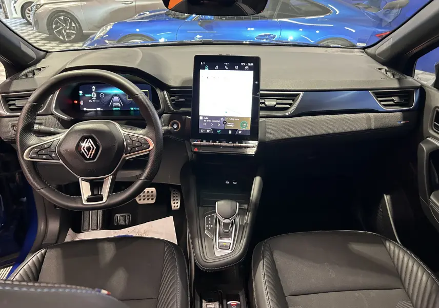 Vue intérieure frontale du Renault Captur II Ph.2 E-Tech bleu Iron, avec tableau de bord numérique et écran tactile central vertical.