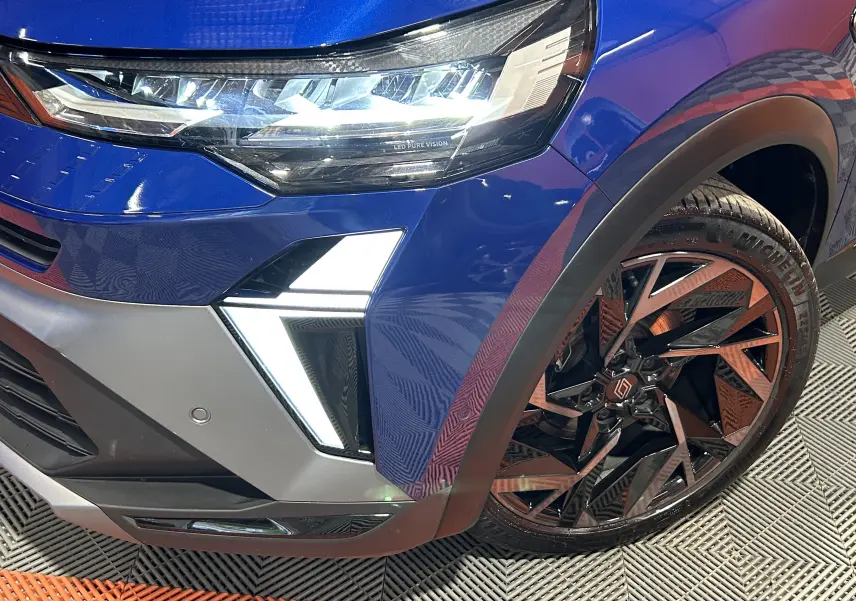 Gros plan sur l’avant droit bleu iron du Renault Captur II Ph.2 avec phare LED et jante alliage noire stylisée.