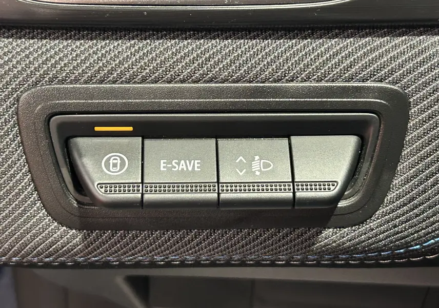 Gros plan sur les boutons de commande E-SAVE et réglage des phares du tableau de bord du Renault Captur bleu Iron.
