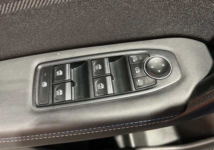 Gros plan sur les commandes des vitres électriques et rétroviseurs côté gauche d’un Renault Captur II Ph.2 bleu Iron.