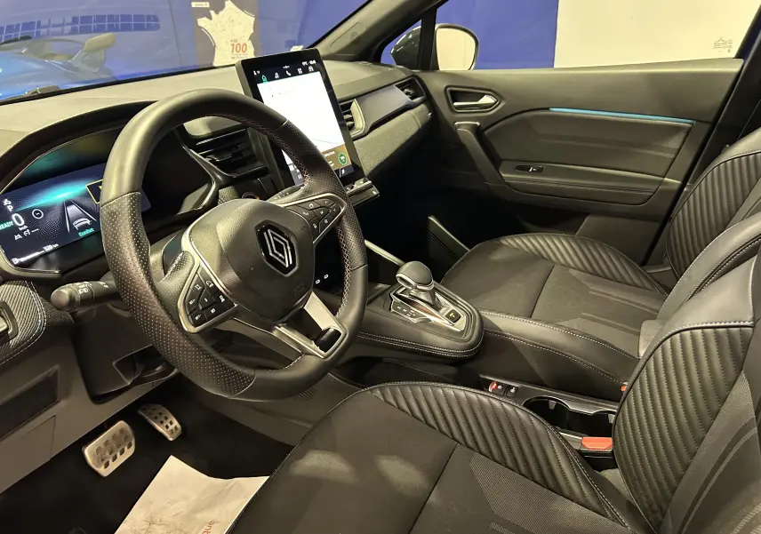 Vue intérieure côté conducteur du Renault Captur bleu Iron 2025, sièges noirs avec logo Alpine brodé.