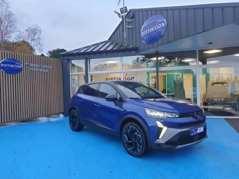 Renault Captur 1.6 E-Tech hybride bleu Iron en 3/4 avant droit, avec jantes alu noires et calandre Esprit Alpine.