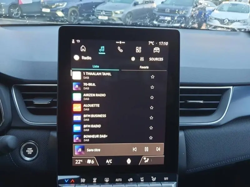 Vue intérieure centrée sur l'écran tactile multimédia du Renault Captur Bleu Iron 2025 avec tableau de bord et bouton start visible.