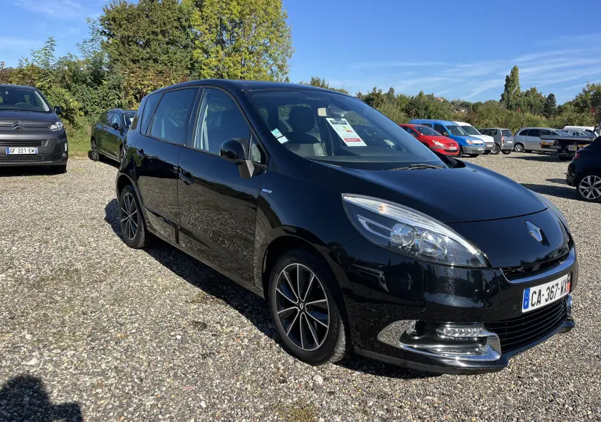 Renault Scénic III noir vue 3/4 avant droit sur parking, jantes alliage et calandre chromée visibles.