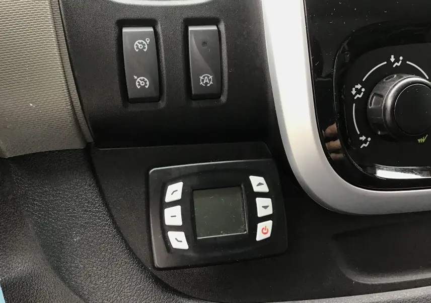 Gros plan sur le tableau de bord noir du Renault Trafic blanc, montrant les commandes du régulateur et du groupe frigorifique.