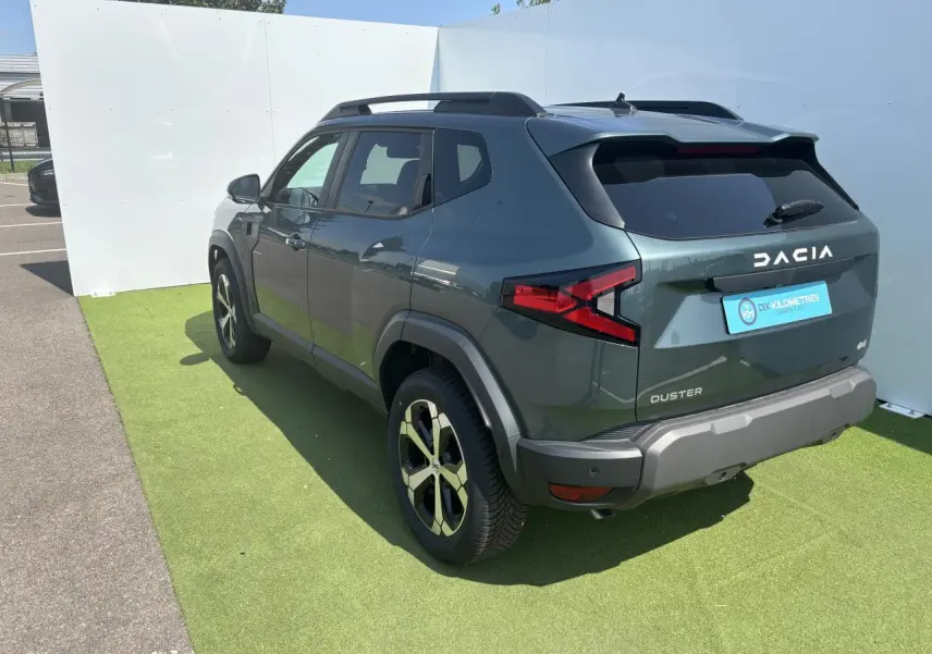 Vue 3/4 arrière droite du Dacia Duster 2025 en Vert Cèdre Métal avec jantes alliage 18 pouces diamantées.
