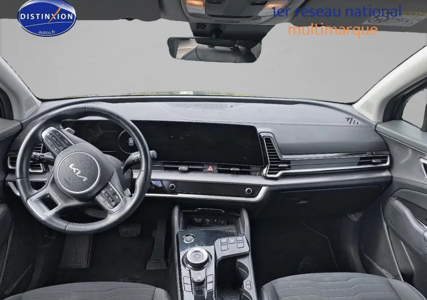 Vue intérieure avant du Kia Sportage 2023 noir, mettant en valeur le tableau de bord moderne et le volant multifonction cuir.