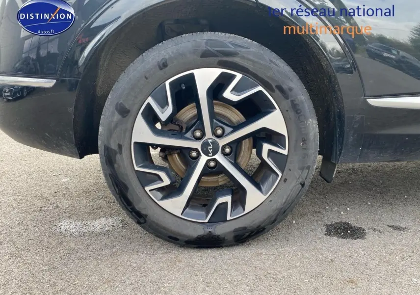 Gros plan sur la roue avant gauche noire du Kia Sportage 2023 avec jante alu bicolore au design moderne.