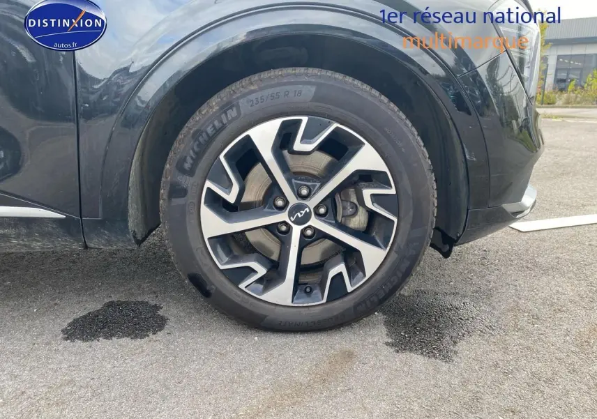 Gros plan sur la roue avant gauche du KIA SPORTAGE noir 2023 avec jante alu au design moderne.