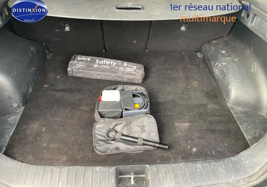 Coffre noir du Kia Sportage 2023 avec kit de sécurité et accessoires de dépannage visibles.