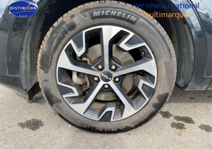 Gros plan sur la roue avant gauche noire du KIA SPORTAGE 2023 avec jante alu et pneu Michelin.