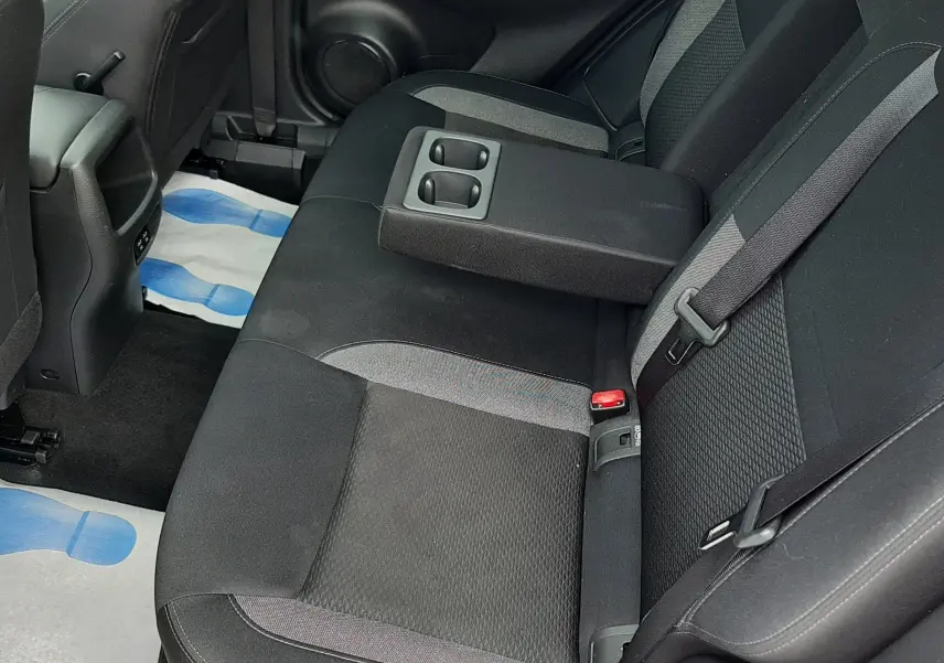 Vue intérieure côté droit des sièges arrière noirs en tissu du Nissan Qashqai blanc 2020 avec accoudoir central rabattable et porte-gobelets intégrés.