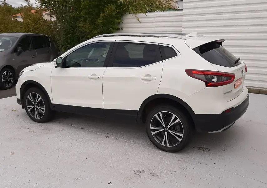 Nissan Qashqai blanc vue de profil côté gauche, avec jantes alliage bicolores et vitres teintées arrière.