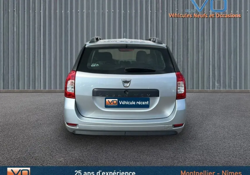 Vue arrière d'une Dacia Logan MCV gris clair 2020 avec barres de toit et feux arrière rouges visibles.