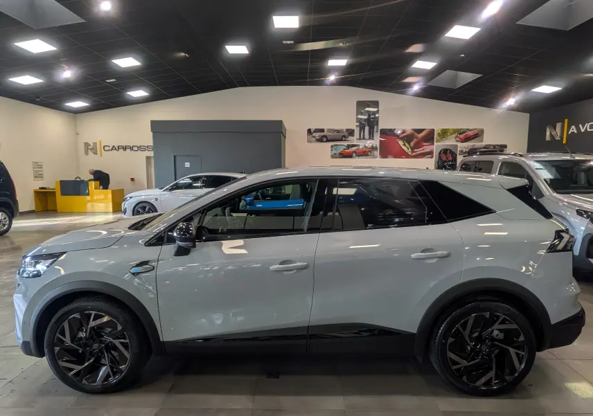 Vue de profil côté gauche du Renault SYMBIOZ E-TECH gris Rafale, avec jantes noires et détails noirs contrastants.