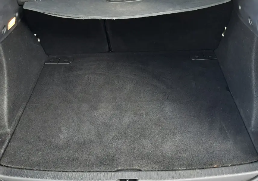Coffre ouvert vu de l'arrière d'une Renault Clio IV Estate beige, montrant l'espace de chargement et la plage arrière.