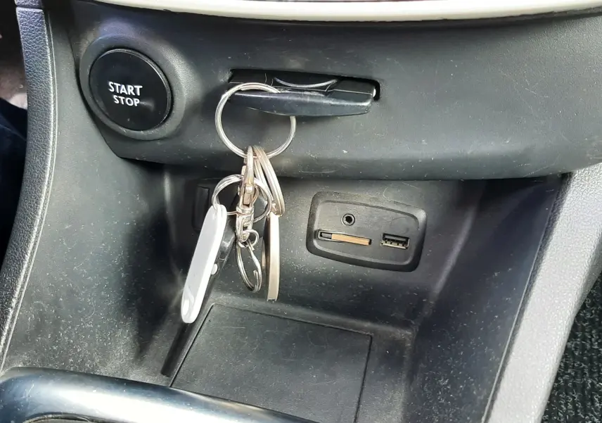 Gros plan sur la console centrale de la Renault Clio IV Estate beige, avec clé insérée et bouton Start/Stop visible.