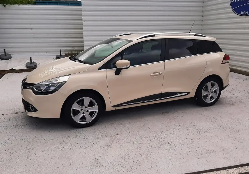 Renault Clio IV Estate beige vue de profil côté gauche, avec barres de toit et jantes alliage 5 branches.