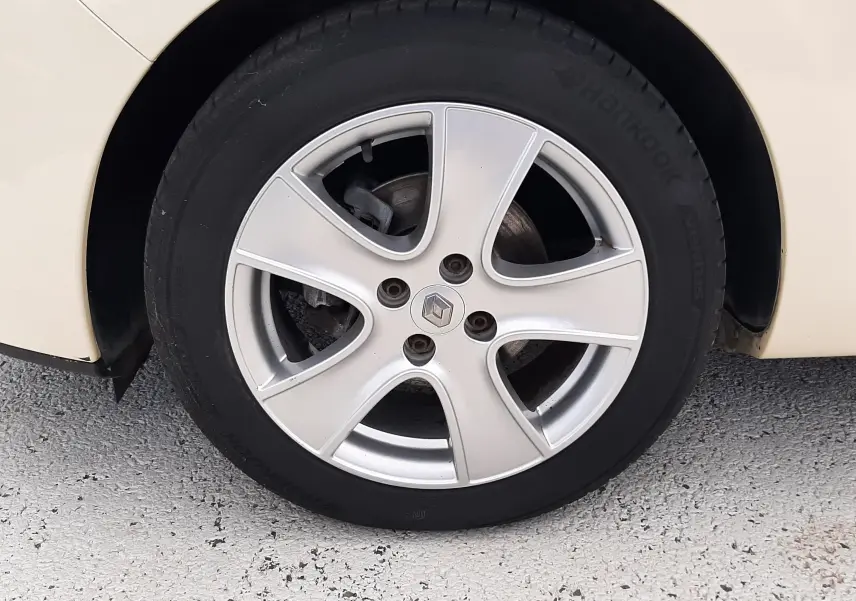 Gros plan sur la roue avant droite beige d'une Renault Clio IV Estate TCe 90ch Intens avec jante alliage argent.