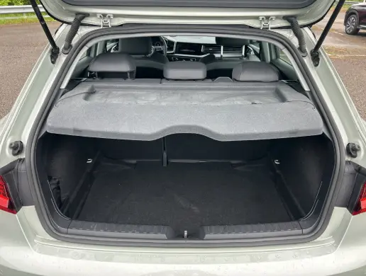 Coffre ouvert vu de l'arrière d'une Audi A1 Sportback gris 2025, avec cache-bagages et sièges arrière rabattables visibles.