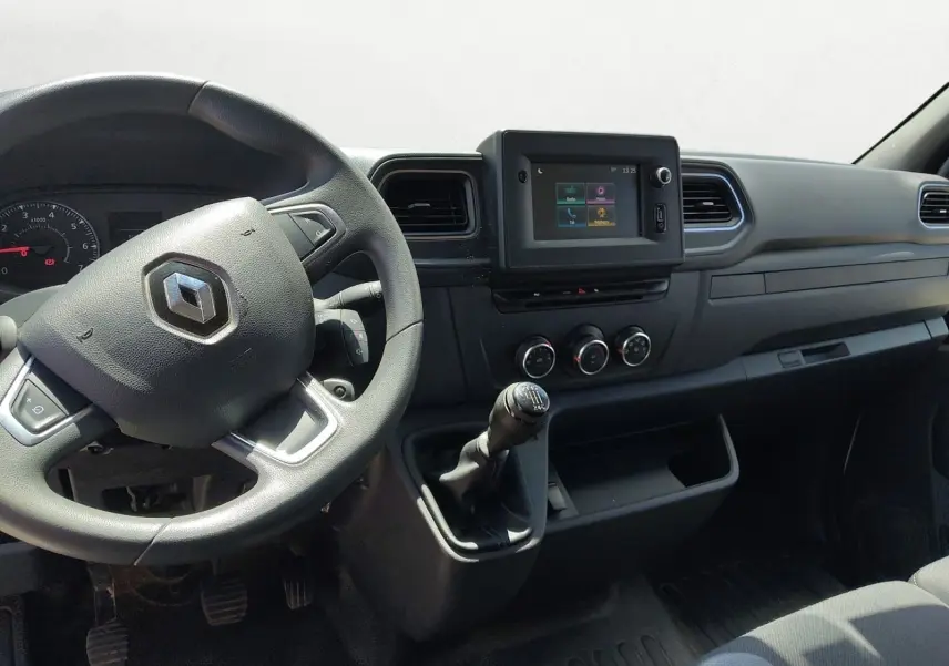 Vue intérieure côté conducteur du tableau de bord noir du Renault Master blanc avec volant, écran tactile et levier de vitesse manuel.
