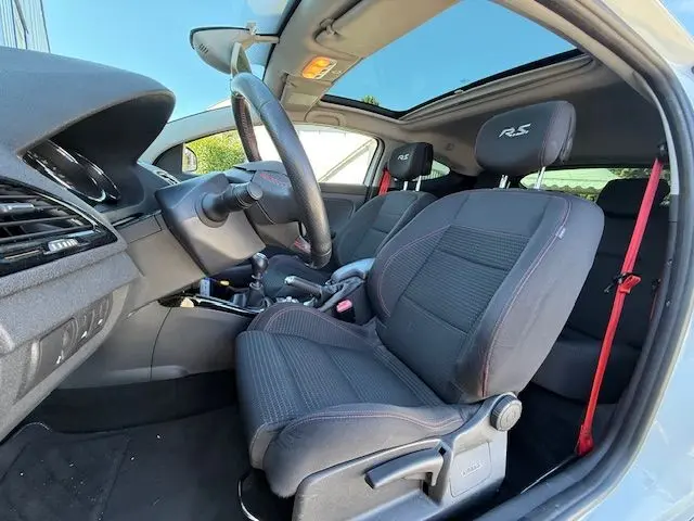 Intérieur de la Renault Mégane III Coupé 2.0T RS vue côté conducteur, sièges tissu noirs avec logo RS et toit ouvrant.